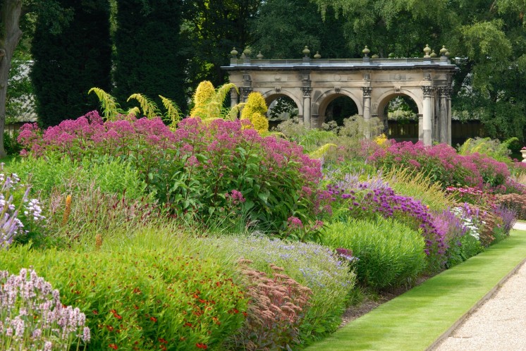 Een brede border met bloeiende vaste planten en grassen.
