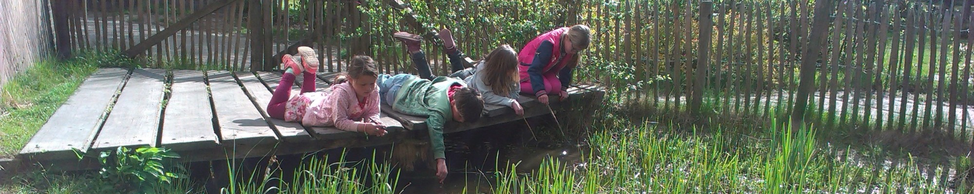 Jonge kinderen spelend met een takje liggend op hun buik.