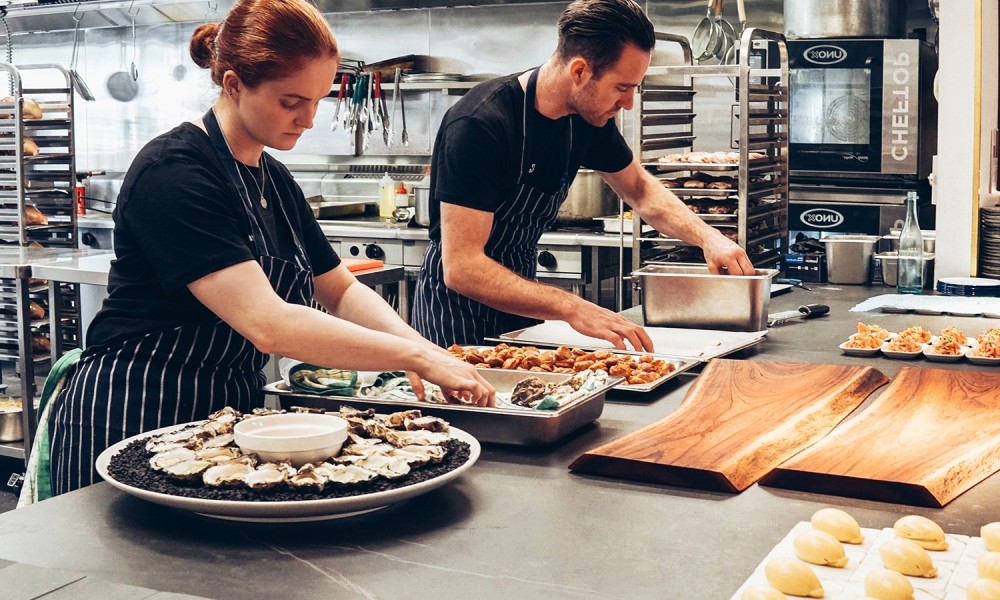 2 personen die in een keuken een gerecht voorbereiden