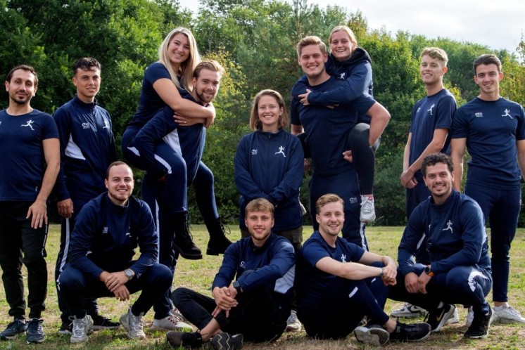 Vier werknemers van sportadviesgroep staan op een grasveld