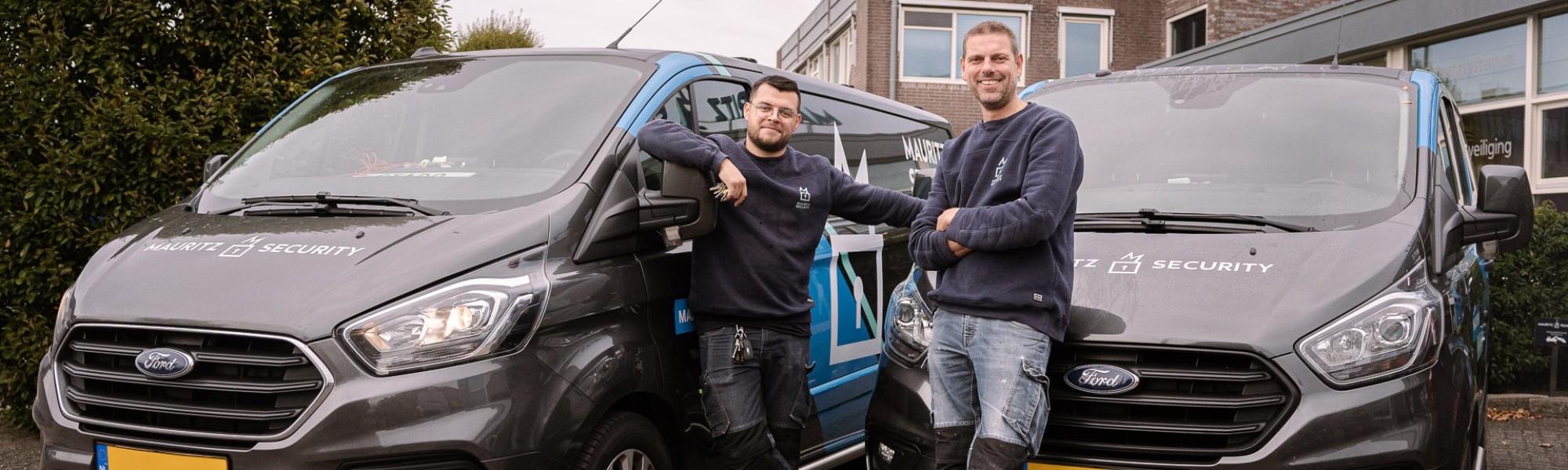 twee monteurs die poseren voor hun bedrijfsbussen