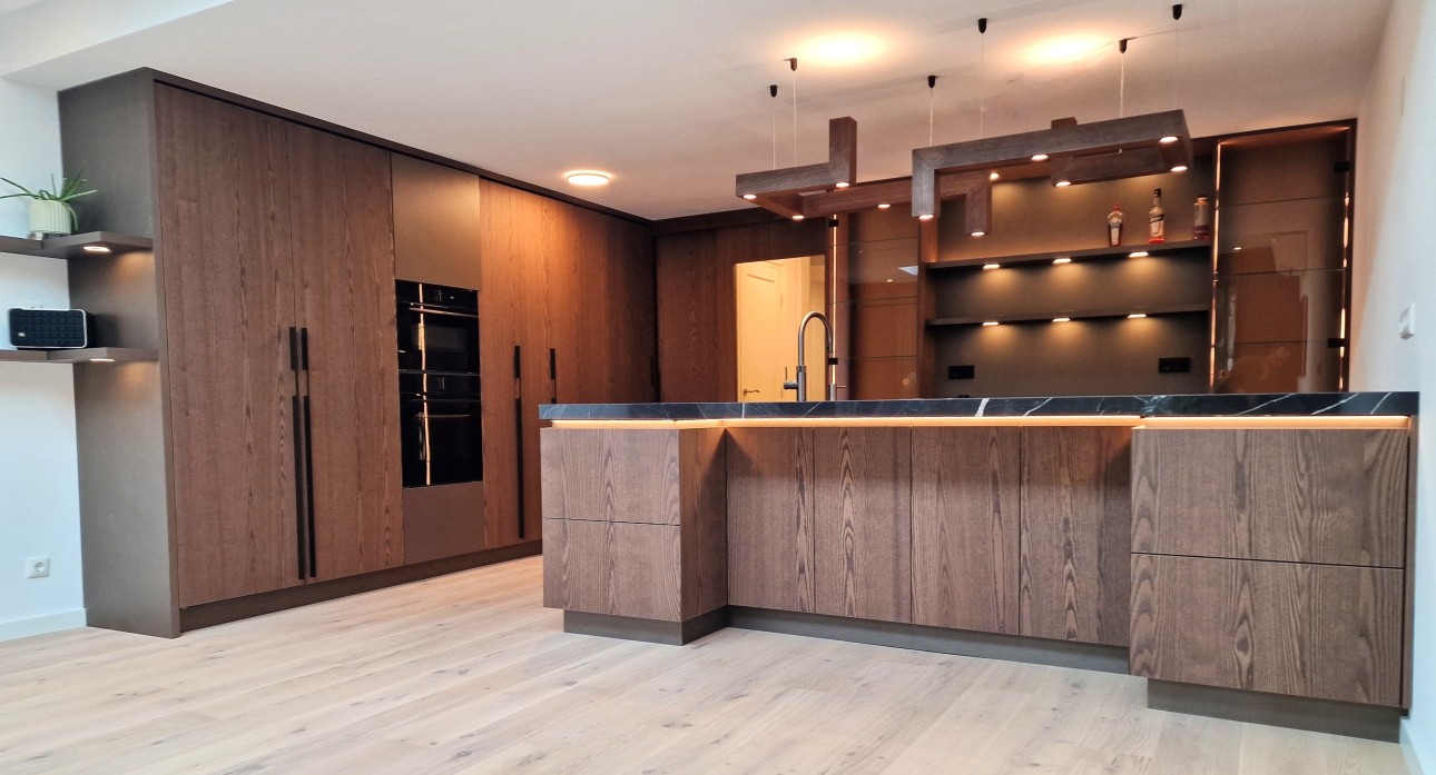 Handgemaakte houten designkeuken met luxe kookeiland / schiereiland en ingebouwde verlichting in de kasten