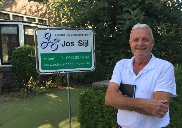 Jos Sijl die naast een bord met zijn logo staat
